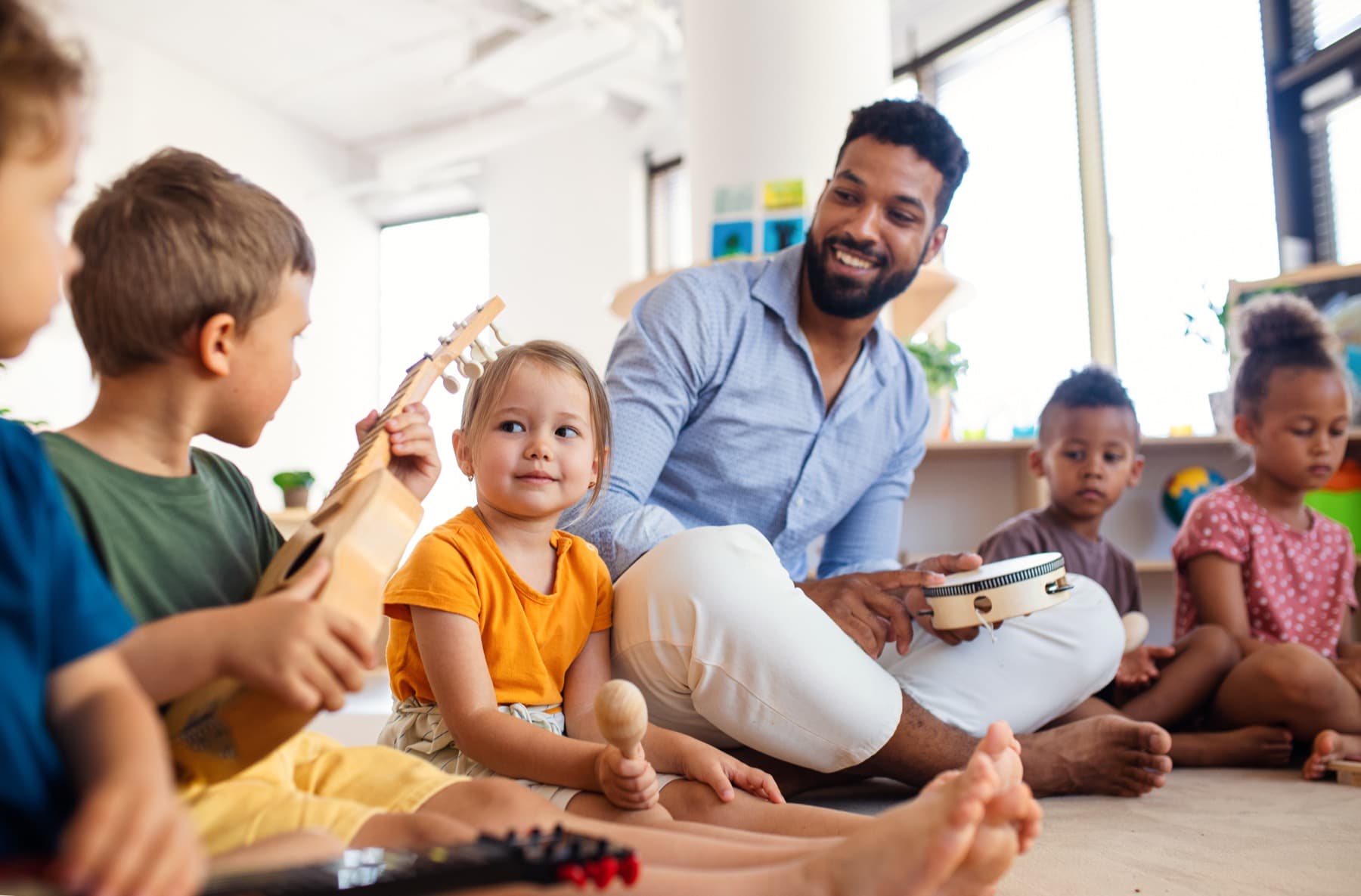Professor conduzindo atividade de musicalização infantil com crianças