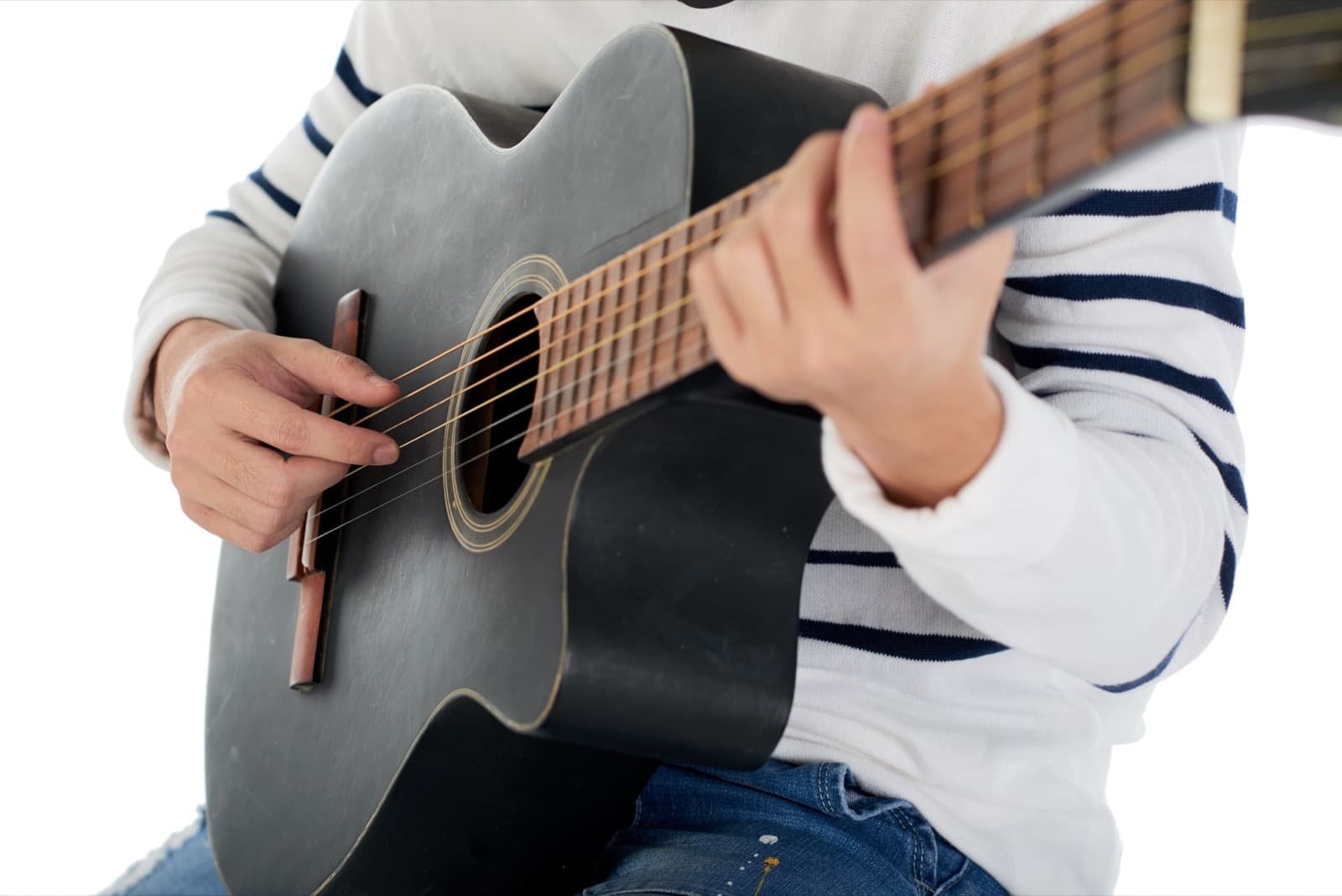 Close das mãos de uma criança tocando violão
