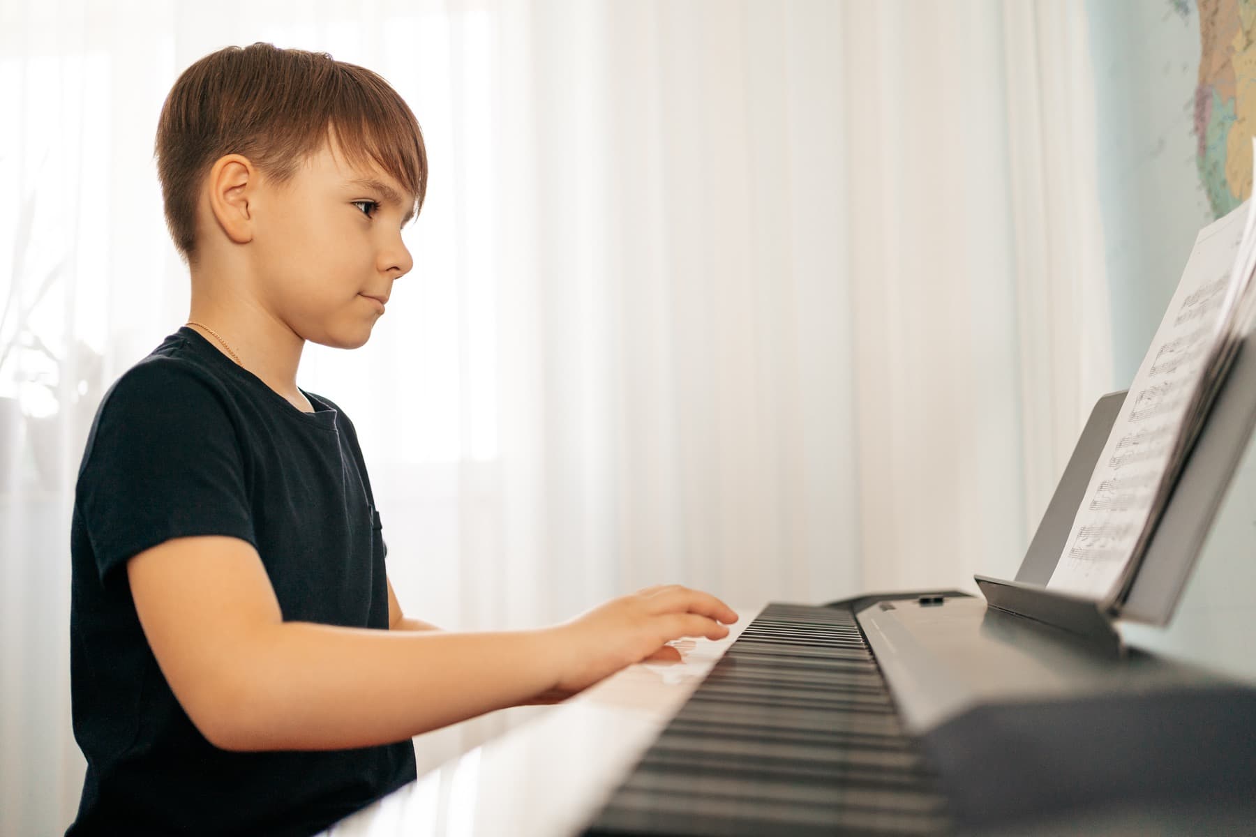 Criança tocando teclado com atenção e observando o processo