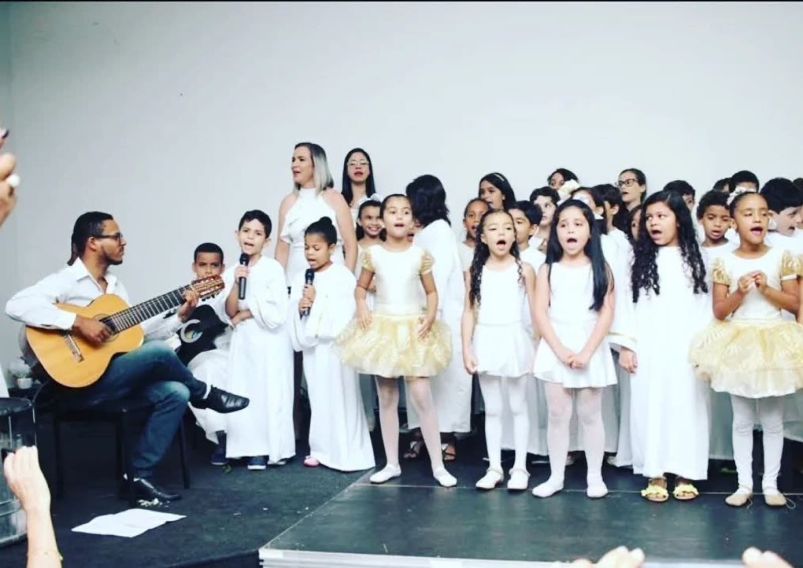 Apresentação musical com crianças em coro e acompanhamento ao violão